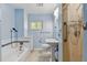 Blue bathroom features a tub and shower combination, updated vanity, and bright natural light at 215 Forrest Dr, Sanford, FL 32773