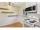 Eat-in kitchen featuring white appliances, wood floors, wainscoting, and a ceiling fan at 215 Forrest Dr, Sanford, FL 32773