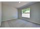 Neutral bedroom featuring carpet, white trim, and a window with backyard view at 2156 Fish Eagle St, Clermont, FL 34714