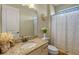 Well-lit bathroom with a granite vanity, a decorative mirror, and a shower with patterned curtains at 2541 Shoal Bass Way, Kissimmee, FL 34746