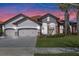 Inviting home showcasing a terra cotta roof, three-car garage, and picturesque sunset backdrop at 2541 Shoal Bass Way, Kissimmee, FL 34746