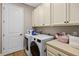 Bright laundry room with white cabinets, washer, dryer, and tile flooring at 2541 Shoal Bass Way, Kissimmee, FL 34746