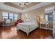 Bright main bedroom featuring hardwood floors, tray ceilings, neutral walls, and abundant natural light through large windows at 2541 Shoal Bass Way, Kissimmee, FL 34746