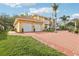 View of the home's three-car garage with a red brick driveway and manicured landscaping at 2747 Kissimmee Bay Cir, Kissimmee, FL 34744
