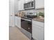 Close-up of kitchen featuring stainless steel oven and microwave, granite countertop, and white cabinets at 3893 Diving Dove Ln, Bartow, FL 33830