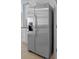 View of the stainless steel refrigerator in modern kitchen with white cabinetry and stone counters at 3893 Diving Dove Ln, Bartow, FL 33830