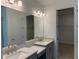 Bathroom with dual sinks, quartz countertops, gray cabinetry, and a large mirror with modern lighting at 4203 Barbuda Ln, Kissimmee, FL 34758