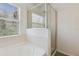 Bright bathroom with combination tub and shower featuring enclosed glass door and large window at 612 Old Pine Ct, Sanford, FL 32773