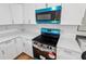 View of the kitchen area with new range and microwave featuring white cabinets and quartz countertops at 859 Neuse Ave, Orlando, FL 32804