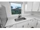 Close up view of a stainless steel kitchen sink, white cabinetry and countertops at 859 Neuse Ave, Orlando, FL 32804