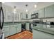Galley kitchen offers light green cabinets, black appliances, tile floors, and great lighting at 1002 Ohanlon Ct, Oviedo, FL 32765