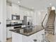 Gourmet kitchen with granite countertops, stainless appliances, and adjacent staircase access to the upper floor at 1195 Boardwalk Pl, Kissimmee, FL 34747