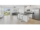 Open-concept kitchen and living area with stainless appliances, island seating, and sliding glass doors at 1195 Boardwalk Pl, Kissimmee, FL 34747