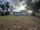 Lush backyard with grass, bordered by trees, a white storage shed, and a partial view of home at 1289 E Hancock Dr, Deltona, FL 32725