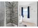 Updated bathroom boasts stylish gray tile in the shower with white fixtures and window at 1315 Overdale St, Orlando, FL 32825