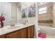 Well-lit bathroom showcasing double sinks, decorative art, and bathtub-shower, for a luxurious feel at 14318 Fieldstone Lake Way, Orlando, FL 32824