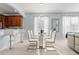Open concept dining room with a glass table and modern white chairs next to the kitchen at 14318 Fieldstone Lake Way, Orlando, FL 32824