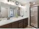 Bathroom with a double sink vanity with dark wood cabinets and glass shower enclosure at 1575 Eucalyptus Way, Davenport, FL 33837
