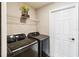 Well-equipped laundry room with modern Samsung washer and dryer, wire shelf, and a convenient entry door at 1575 Eucalyptus Way, Davenport, FL 33837