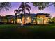 Beautiful twilight shot of one-story home with lights on showing lush green lawn, two large palm trees at 2008 Water Key Dr, Windermere, FL 34786