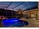 Beautiful screened-in pool with stone tile deck, outdoor seating, and tranquil waterfall feature at dusk at 2008 Water Key Dr, Windermere, FL 34786