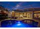 Beautiful screened-in pool with travertine tile deck, outdoor seating, and waterfall feature at dusk at 2008 Water Key Dr, Windermere, FL 34786