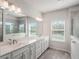 Bright bathroom featuring double vanity with white cabinets, quartz countertops, and walk-in shower at 2189 Weatherly Way, Orlando, FL 32820