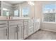 Bathroom featuring a double vanity with white cabinets and a large mirror, brightened by natural light at 2189 Weatherly Way, Orlando, FL 32820
