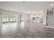 Open floor plan showcasing the spacious living room, modern kitchen and staircase with wood-look floors and sliding glass doors at 2189 Weatherly Way, Orlando, FL 32820