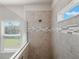 Tiled shower featuring a rainfall showerhead, glass partition, and window for natural light at 2189 Weatherly Way, Orlando, FL 32820