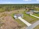 An aerial view shows this lovely single-Gathering home with lush green surroundings and a large driveway plus carport at 2430 Park Ave, Indian Lake Estates, FL 33855
