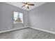 This bedroom features stylish gray wood-look tile flooring, a ceiling fan, and a bright window with floral curtains at 2430 Park Ave, Indian Lake Estates, FL 33855