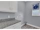 This laundry room has granite countertops, white cabinets, and a window with a decorative sign at 2430 Park Ave, Indian Lake Estates, FL 33855