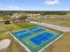 Overhead view of the tennis courts with bright blue playing surfaces and green perimeters, with the clubhouse in the background at 2430 Park Ave, Indian Lake Estates, FL 33855