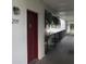 Hallway view of unit #2597 entrance with red door, walkway, and tropical landscaping at 2597 Oak Park Way # 205, Orlando, FL 32822