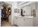 Clean bathroom featuring double sinks, a large mirror with vanity lighting, and walk-in closet at 26 Pied Ct, Orlando, FL 32828