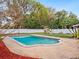 Backyard showcasing in-ground pool, concrete patio, lush lawn, playset, and white perimeter fence at 2900 E Grant Ave, Orlando, FL 32806