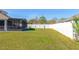 Large, grassy backyard with a screened-in patio and white vinyl fencing for privacy at 3006 Mandolin Dr, Kissimmee, FL 34744