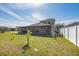 Spacious backyard with a screened patio, lush green lawn, and white vinyl fencing at 3006 Mandolin Dr, Kissimmee, FL 34744