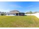 Home's large, grassy backyard with screened patio and privacy fence at 3006 Mandolin Dr, Kissimmee, FL 34744