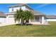 Inviting two-story home with a green lawn and tropical palm trees enhancing the curb appeal at 3006 Mandolin Dr, Kissimmee, FL 34744
