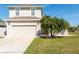 Charming two-story home featuring a well-manicured lawn, a two-car garage, and a beautiful palm tree at 3006 Mandolin Dr, Kissimmee, FL 34744