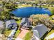 Aerial view of a lakeside home with a brick driveway, solar panels, and mature trees at 352 Misty Oaks Run, Casselberry, FL 32707