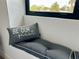 Close-up of a window nook with gray cushions and a decorative pillow in a sunlit bedroom at 382 Riverside Dr, Ormond Beach, FL 32176