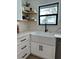 Modern kitchen sink with white cabinetry, open shelving, sleek black hardware, and views of the lake at 382 Riverside Dr, Ormond Beach, FL 32176