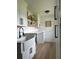 Bright laundry room with white cabinets, open wood shelving, stylish black hardware, and a farmhouse sink at 382 Riverside Dr, Ormond Beach, FL 32176