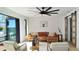 A living room featuring a ceiling fan, neutral furniture, and scenic waterfront views from large windows at 382 Riverside Dr, Ormond Beach, FL 32176
