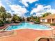 Community pool surrounded by lush landscaping, lounge chairs, and a building entrance at 4715 Coral Castle Dr, Kissimmee, FL 34746