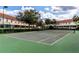 Well-maintained community tennis court surrounded by lush landscaping, residential buildings and partly cloudy sky at 4715 Coral Castle Dr, Kissimmee, FL 34746