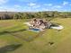 Aerial view of the expansive property showcasing the pool, house, large yard, fence, and surrounding greenery at 5500 State Road 33, Clermont, FL 34714
